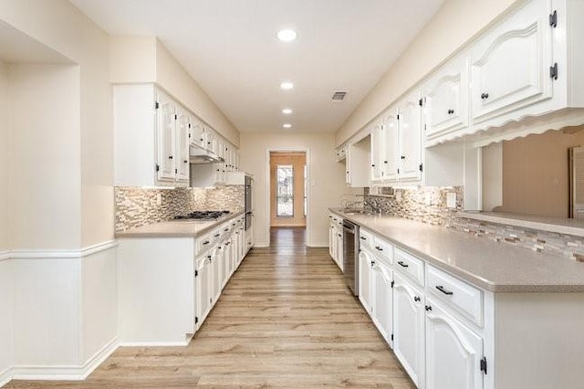 kitchen with stainless steel appliances, backsplash, white cabinets, and light hardwood / wood-style floors