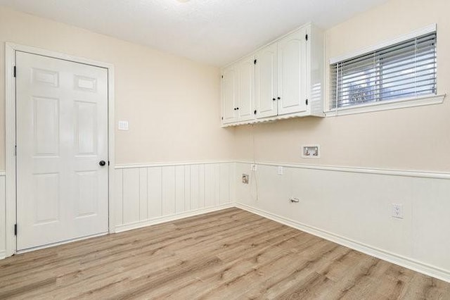 clothes washing area with cabinets, washer hookup, and light hardwood / wood-style floors