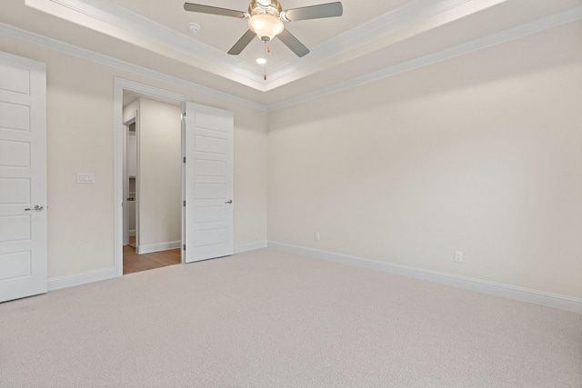 unfurnished bedroom featuring ceiling fan, light colored carpet, ornamental molding, and a raised ceiling