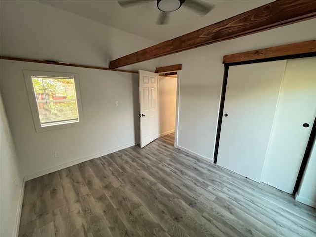 unfurnished bedroom featuring vaulted ceiling with beams, ceiling fan, and light wood-type flooring