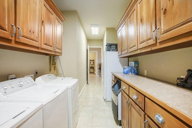 clothes washing area with washer and dryer, cabinets, and light tile patterned flooring