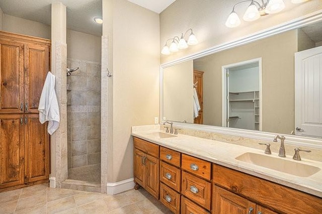 bathroom featuring vanity, tile patterned flooring, and a tile shower