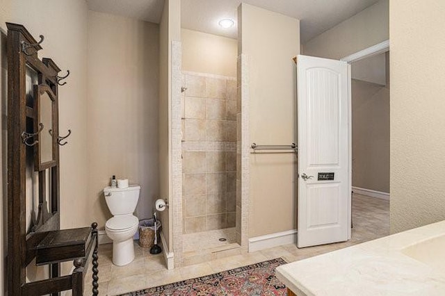 bathroom featuring tile patterned floors, toilet, vanity, and a tile shower