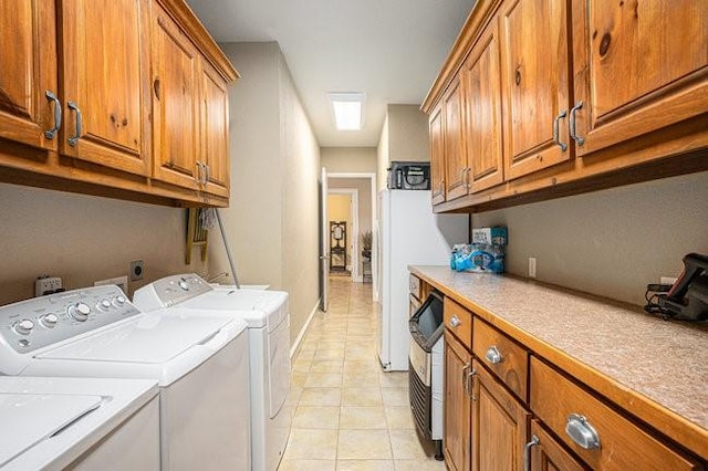 clothes washing area with light tile patterned floors, washing machine and dryer, and cabinets