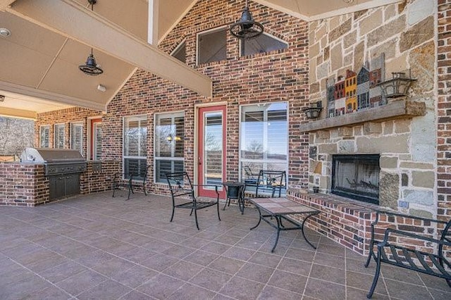 view of patio with an outdoor kitchen, area for grilling, and an outdoor stone fireplace