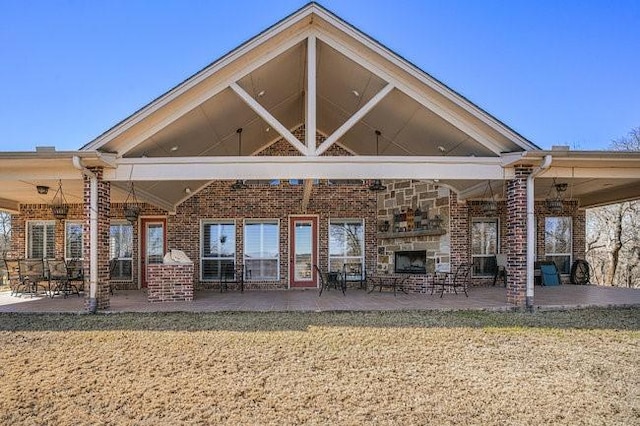 rear view of property featuring a patio, a stone fireplace, and a yard