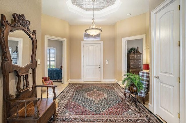 foyer with a raised ceiling and ornamental molding