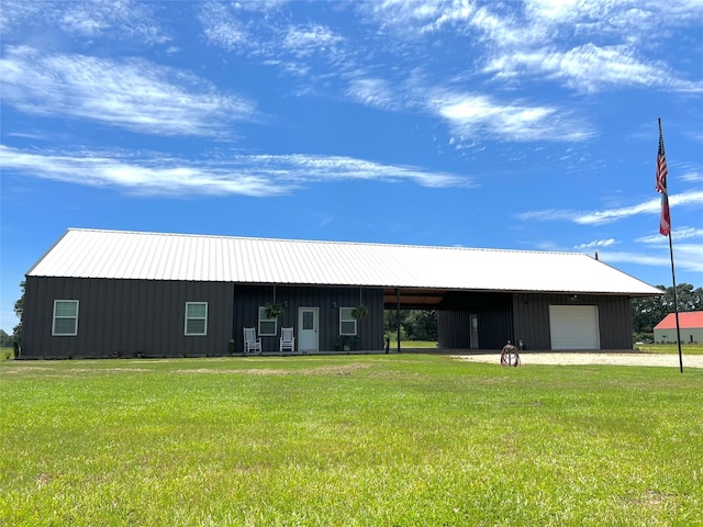 view of front of property with a garage, metal roof, an outdoor structure, board and batten siding, and a front yard