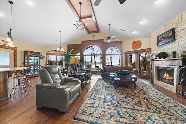 living room featuring dark wood-type flooring, high vaulted ceiling, beamed ceiling, a fireplace, and ceiling fan with notable chandelier