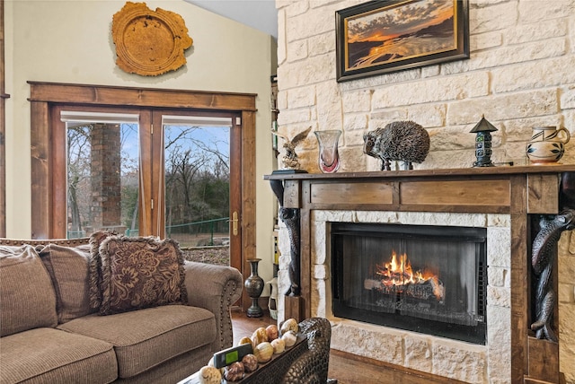 living room with wood-type flooring and a stone fireplace