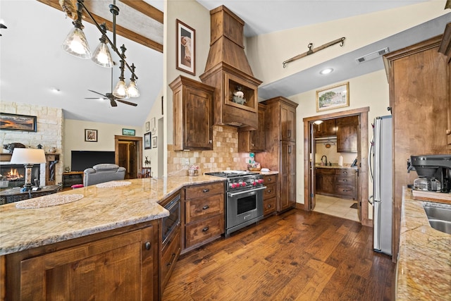 kitchen featuring lofted ceiling, light stone counters, stainless steel appliances, and decorative light fixtures