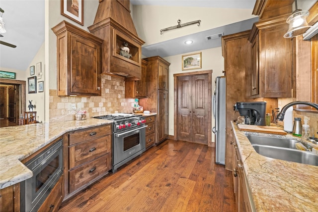 kitchen with stainless steel appliances, vaulted ceiling, light stone countertops, and sink