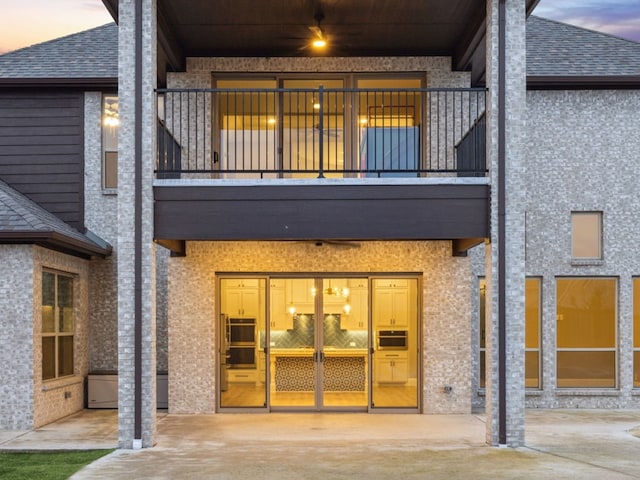 back house at dusk featuring a balcony