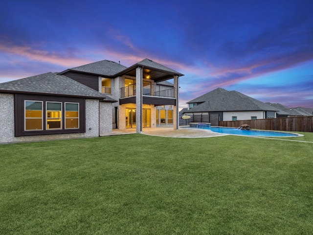 back house at dusk with a fenced in pool, a lawn, a patio, pool water feature, and a balcony