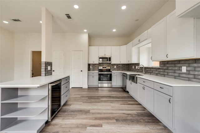 kitchen featuring wine cooler, sink, white cabinetry, and stainless steel appliances