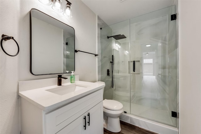 bathroom featuring vanity, hardwood / wood-style floors, a shower with door, and toilet