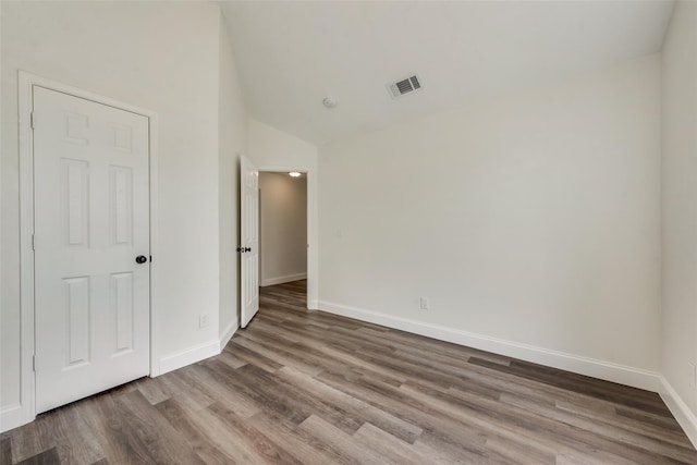 unfurnished room with lofted ceiling and hardwood / wood-style floors