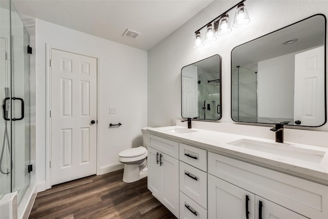 bathroom featuring vanity, wood-type flooring, a shower with door, and toilet