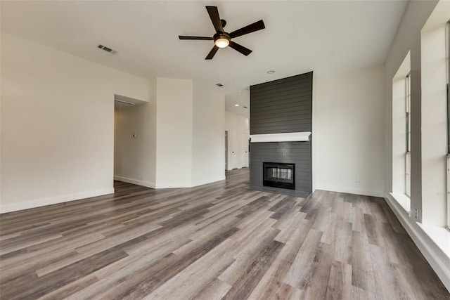 unfurnished living room featuring hardwood / wood-style flooring, ceiling fan, and a fireplace