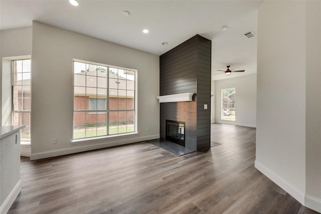 unfurnished living room featuring ceiling fan, a fireplace, and wood-type flooring