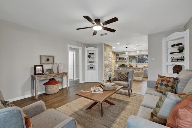 living room with dark wood-type flooring and ceiling fan