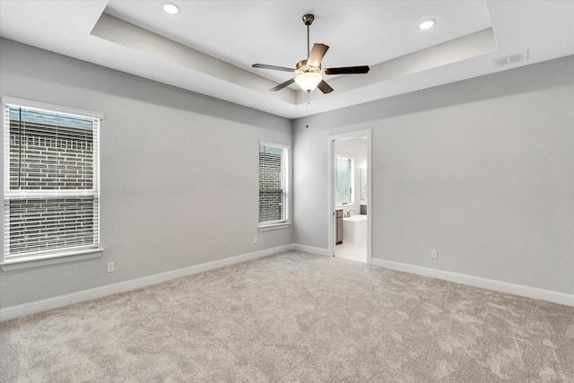 carpeted empty room featuring a raised ceiling and ceiling fan