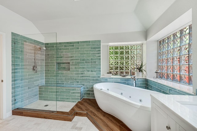 bathroom featuring hardwood / wood-style flooring, tile walls, vanity, vaulted ceiling, and shower with separate bathtub