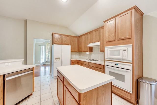 kitchen featuring light tile patterned flooring, tasteful backsplash, a center island, vaulted ceiling, and white appliances