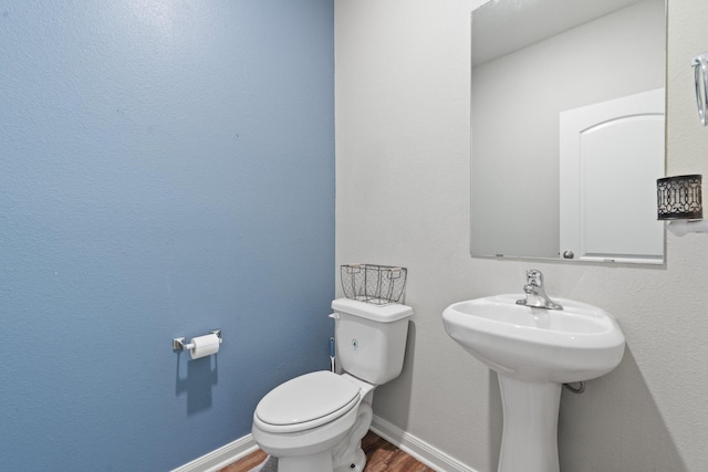 bathroom with hardwood / wood-style flooring, toilet, and sink