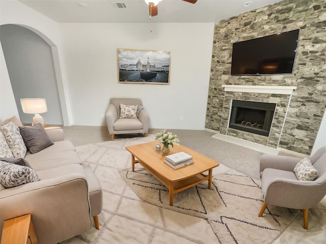 living room featuring light carpet, a fireplace, and ceiling fan