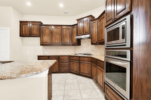 kitchen featuring under cabinet range hood, tasteful backsplash, visible vents, and stainless steel appliances