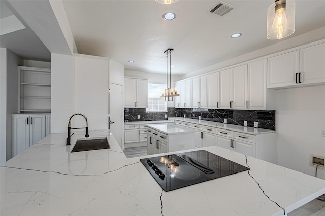 kitchen with sink, decorative light fixtures, black electric stovetop, light stone countertops, and white cabinets