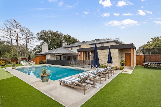 view of swimming pool featuring a yard, a patio, and a trampoline