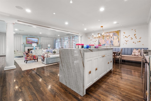 kitchen with a kitchen island, decorative light fixtures, decorative columns, white cabinets, and crown molding