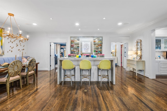 kitchen with dark hardwood / wood-style flooring, crown molding, pendant lighting, and a kitchen breakfast bar