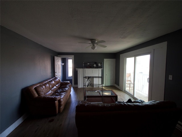 living room featuring hardwood / wood-style flooring, ceiling fan, and a textured ceiling