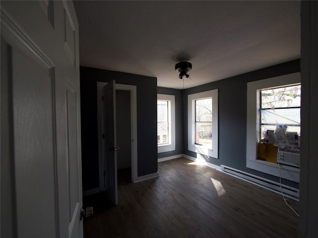 spare room featuring dark wood-type flooring and a baseboard radiator