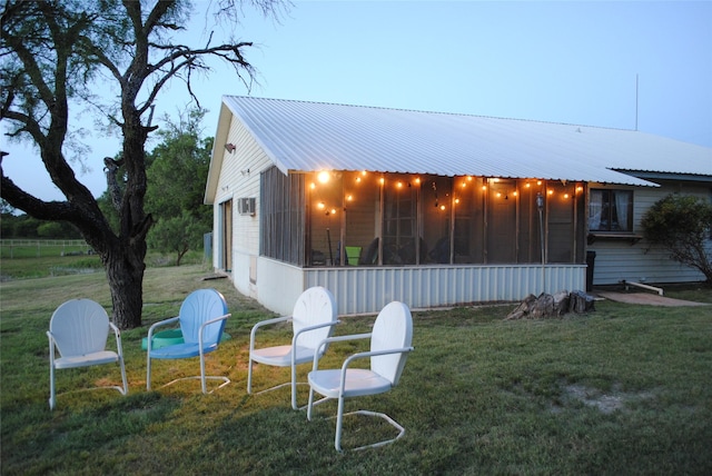 property exterior at dusk with a sunroom and a lawn