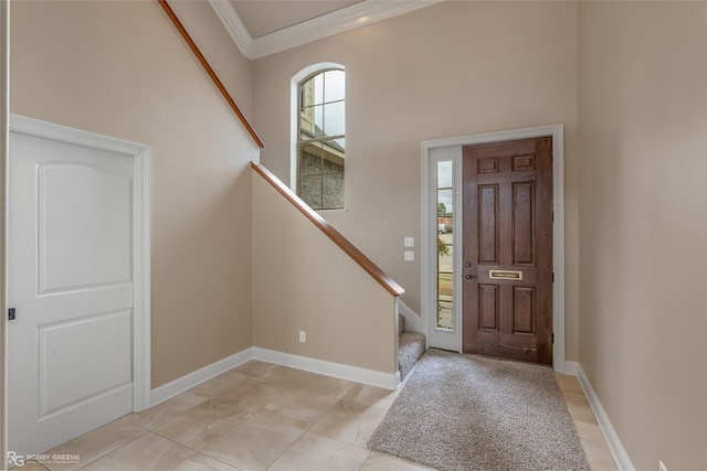 foyer featuring stairs, ornamental molding, a towering ceiling, and baseboards