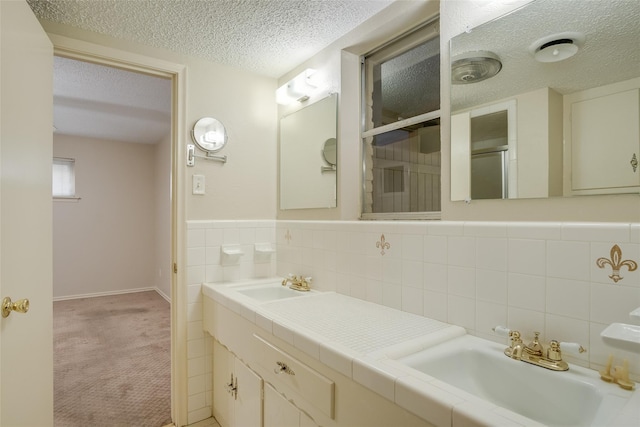 bathroom with vanity, a textured ceiling, and tile walls