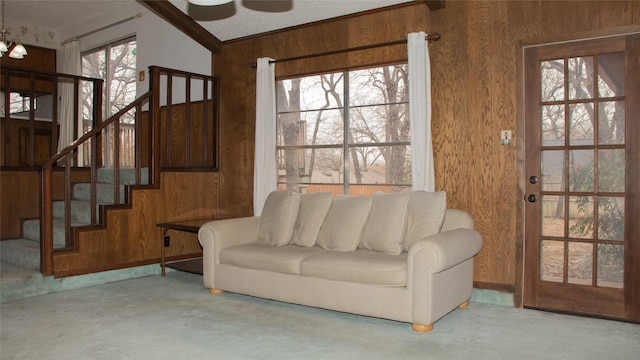 living room featuring concrete floors, wood walls, stairs, and ornamental molding