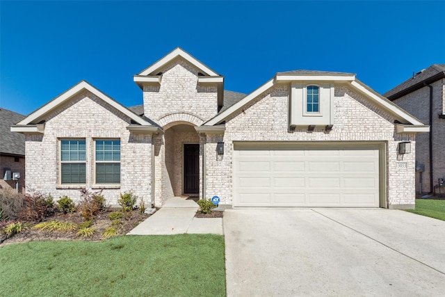 french country style house featuring an attached garage, a front yard, concrete driveway, and brick siding