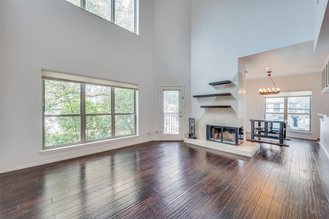 living room with hardwood / wood-style floors, plenty of natural light, a chandelier, and a high ceiling