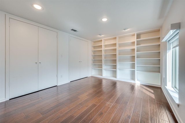 spare room featuring hardwood / wood-style flooring and built in shelves