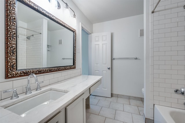 full bathroom featuring tiled shower / bath, backsplash, vanity, toilet, and tile patterned floors