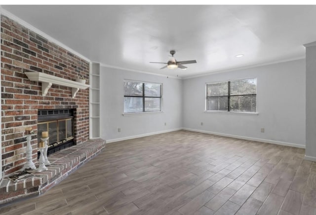 unfurnished living room featuring a brick fireplace, wood-type flooring, ornamental molding, and ceiling fan