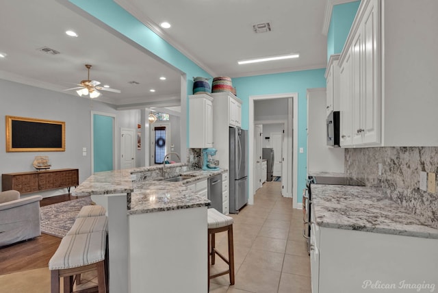 kitchen with a breakfast bar, kitchen peninsula, sink, and white cabinets