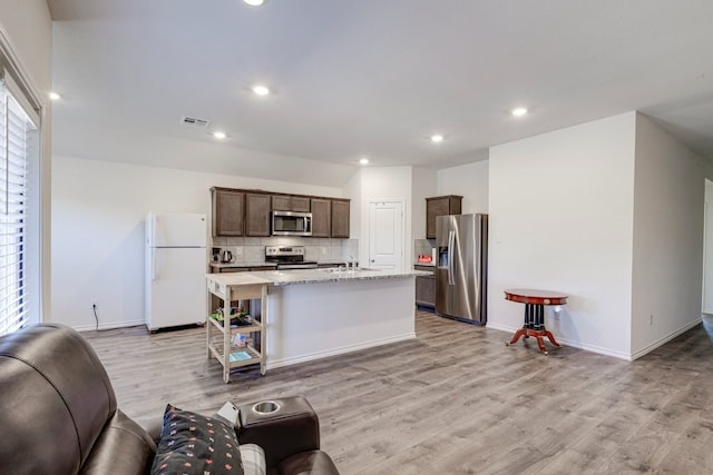 kitchen with tasteful backsplash, visible vents, dark brown cabinetry, open floor plan, and stainless steel appliances