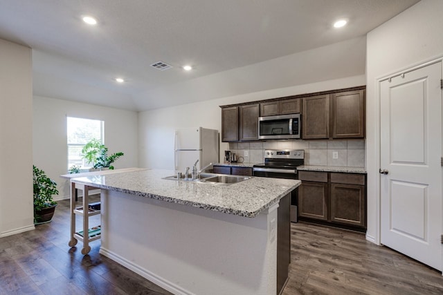 kitchen with visible vents, an island with sink, tasteful backsplash, dark wood-style floors, and stainless steel appliances