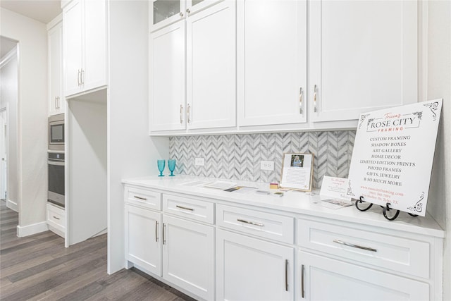 kitchen with white cabinetry, stainless steel appliances, dark hardwood / wood-style floors, and backsplash